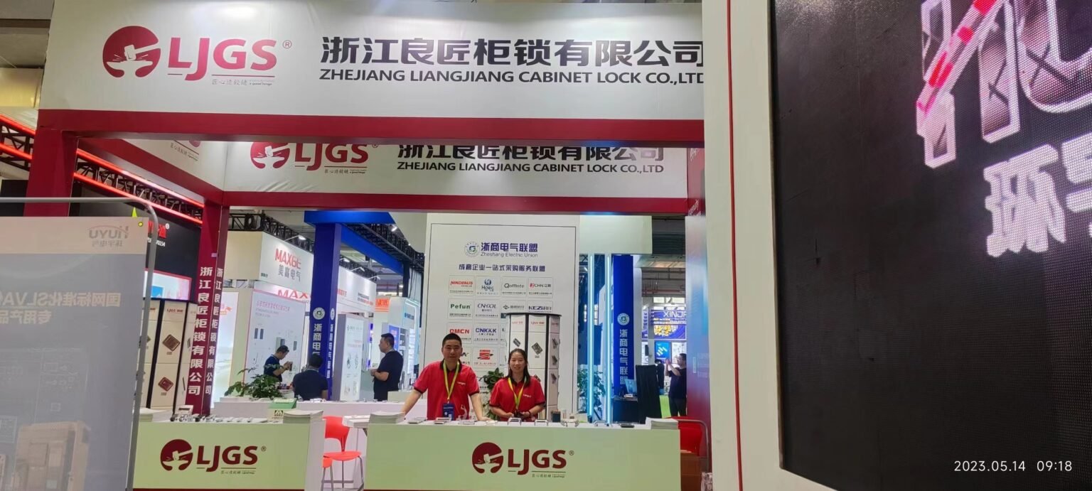 Booth of Zhejiang Liangjiang Cabinet Lock Co., Ltd. at the Wenzhou Energy Storage Exhibition, with two people standing behind a counter displaying products. The company name is prominently featured with logo and signage above.