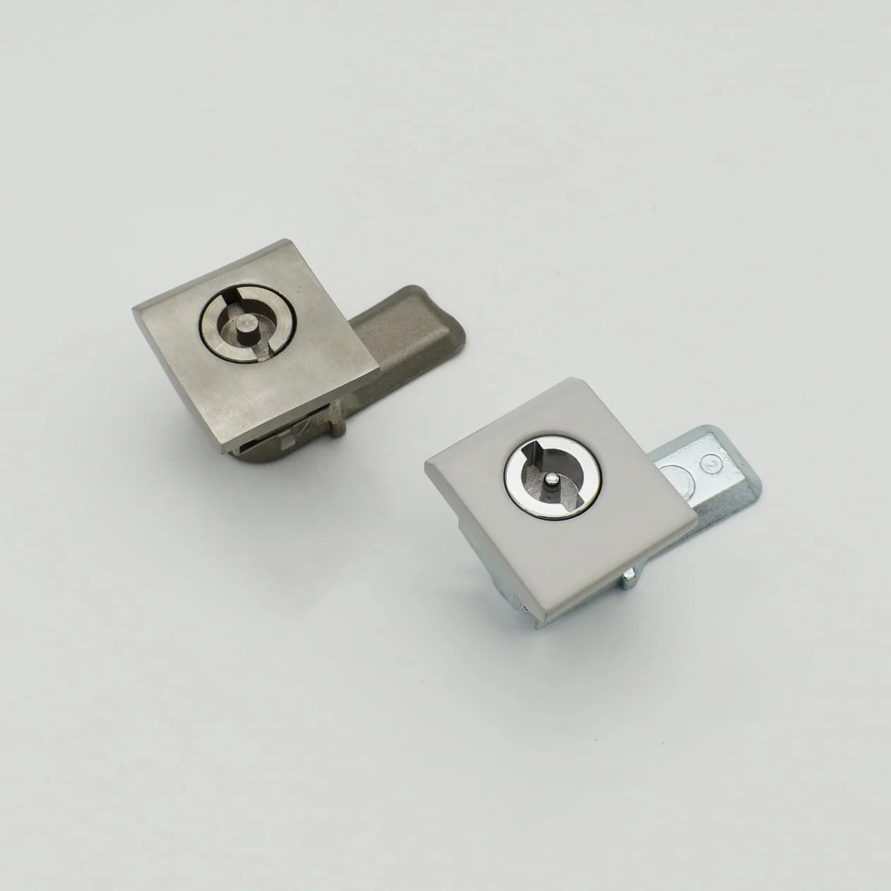 DSC_2317 showcases a pair of square cam locks featuring sleek metal finishes, artfully displayed against a simple white backdrop.