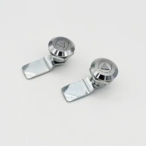 Two MS773 cam locks with flat latches, each adorned with engraved triangular icons on their circular tops, are placed on a plain white surface.